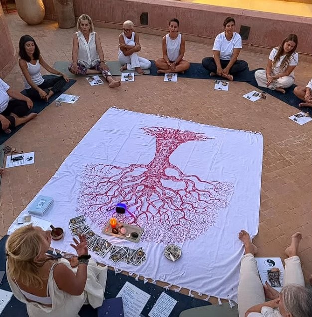 Séance de méditation en cercle dans le patio du Riad Vendôme Marrakech lors d'un stage de yoga — tapis bleus, tissu arbre de vie au centre